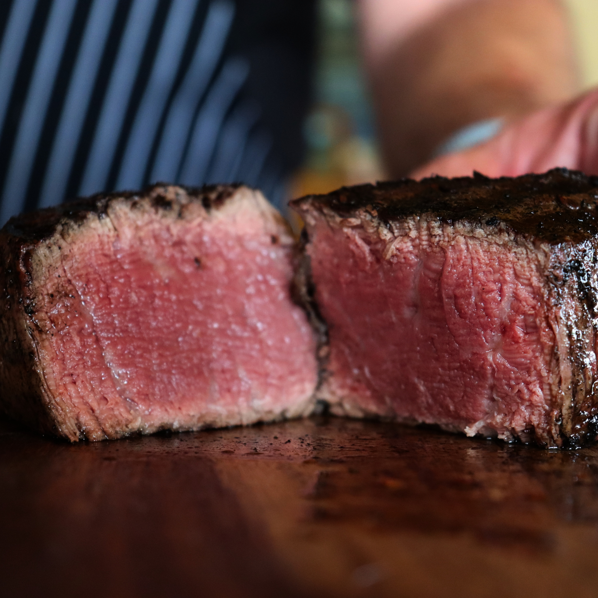 A perfectly grilled, medium-rare USDA Prime Black Angus filet mignon steak sliced open on a dark wood cutting board to show its juicy texture, direct from Winston Cattle Co.
