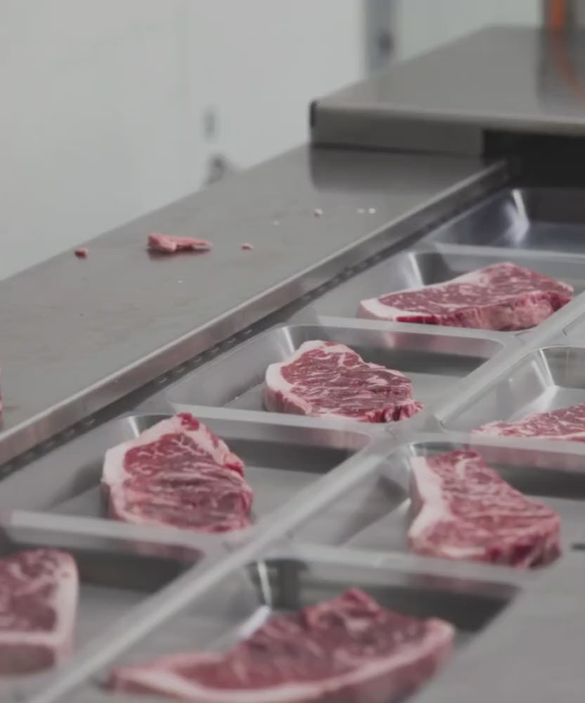 Load video: Inside the Winston Cattle Co Fort Worth facility: an automated cutting machine slicing a whole USDA Prime loin into thick, uniform steaks.