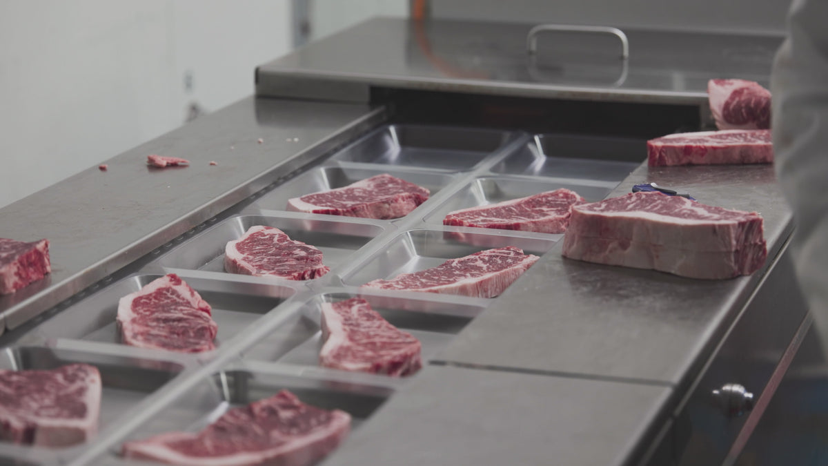 Load video: Inside the Winston Cattle Co Fort Worth facility: an automated cutting machine slicing a whole USDA Prime loin into thick, uniform steaks.