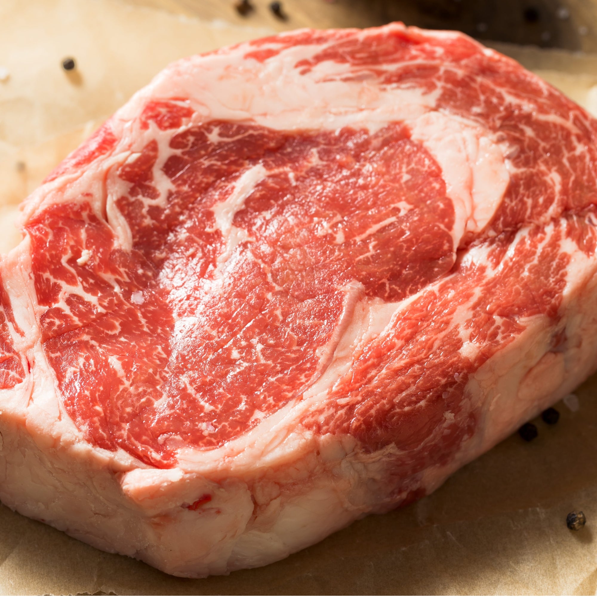A raw, thickly cut boneless USDA Prime Black Angus ribeye steak displaying exceptional intramuscular fat marbling, custom-processed at Winston Cattle Co.