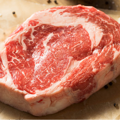 A raw, thickly cut boneless USDA Prime Black Angus ribeye steak displaying exceptional intramuscular fat marbling, custom-processed at Winston Cattle Co.